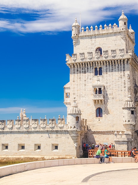 People sitting near Belem Tower in Lisbon, Portugal.