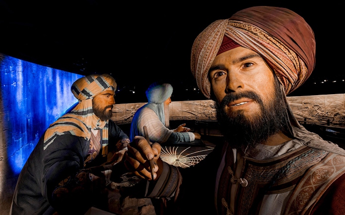 Three historical figures in traditional attire at Expo City Dubai exhibit.