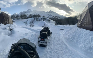 Snowmobiles on a snowy trail with mountains in Ushuaia.