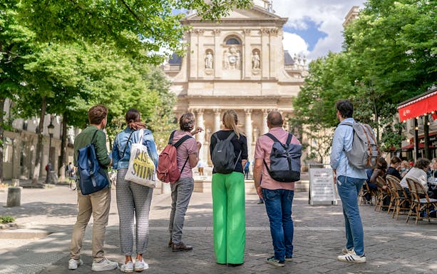 Tourists in Latin Quarter Paris on a guided walking tour facing historic building.