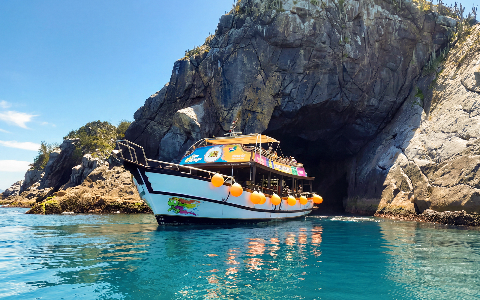 Boat entering Gruta Azul cave on tour in Arraial do Cabo, Brazil.