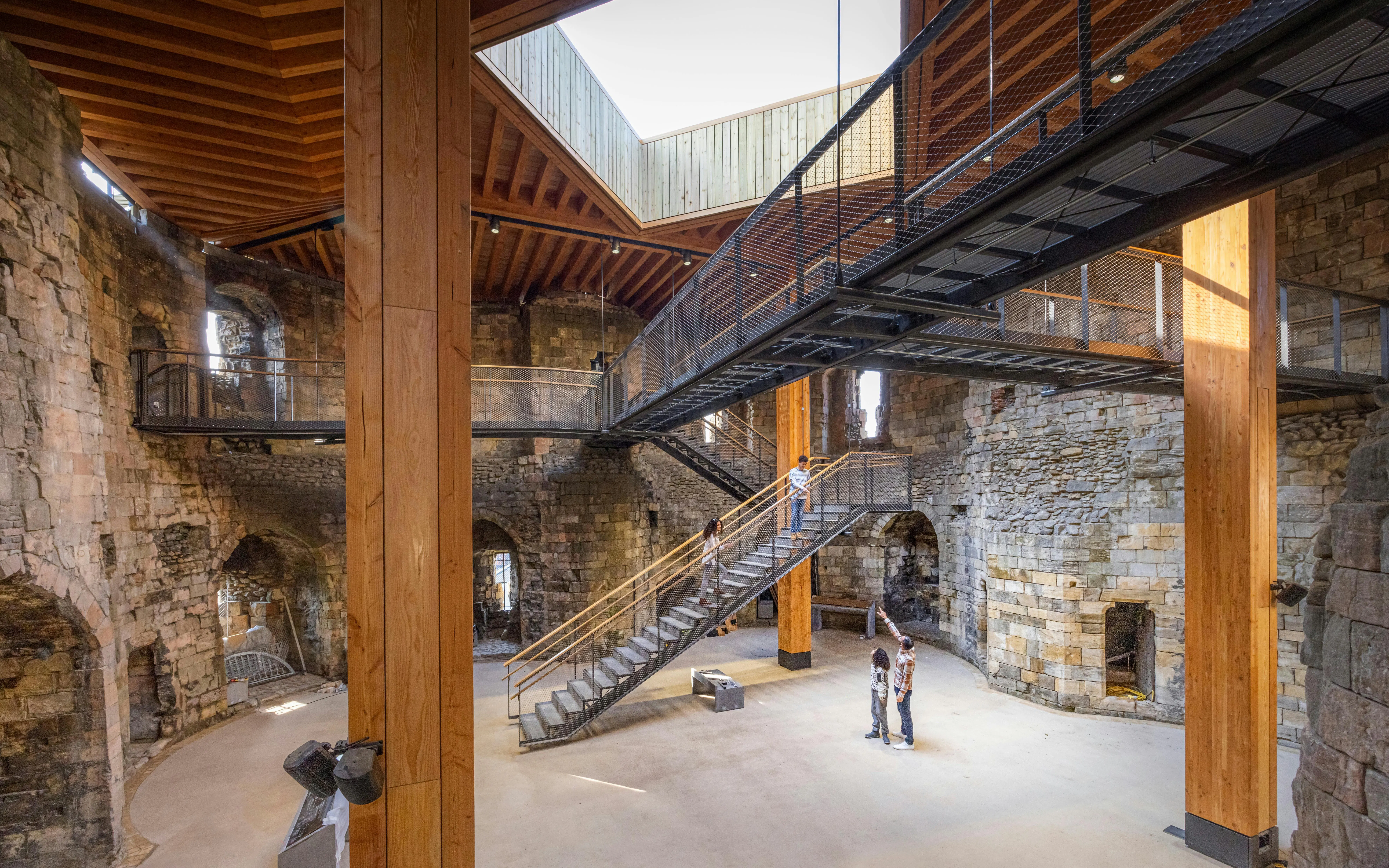 Interior view of Clifford's Tower with visitors exploring the historic stone walls and modern walkways.