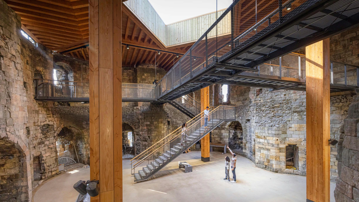 Interior view of Clifford's Tower with visitors exploring the historic stone walls and modern walkways.