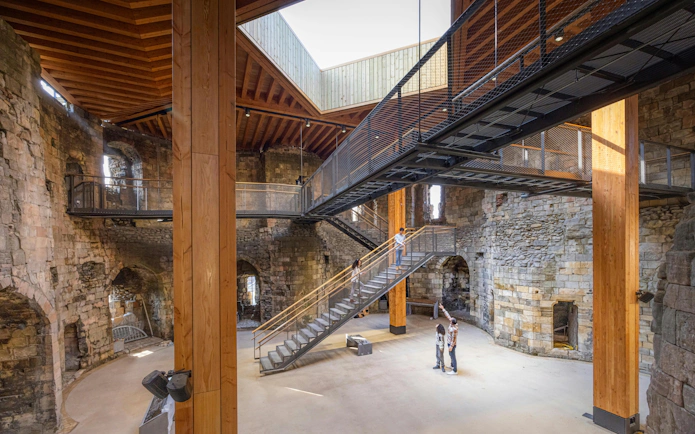 Interior view of Clifford's Tower with visitors exploring the historic stone walls and modern walkways.