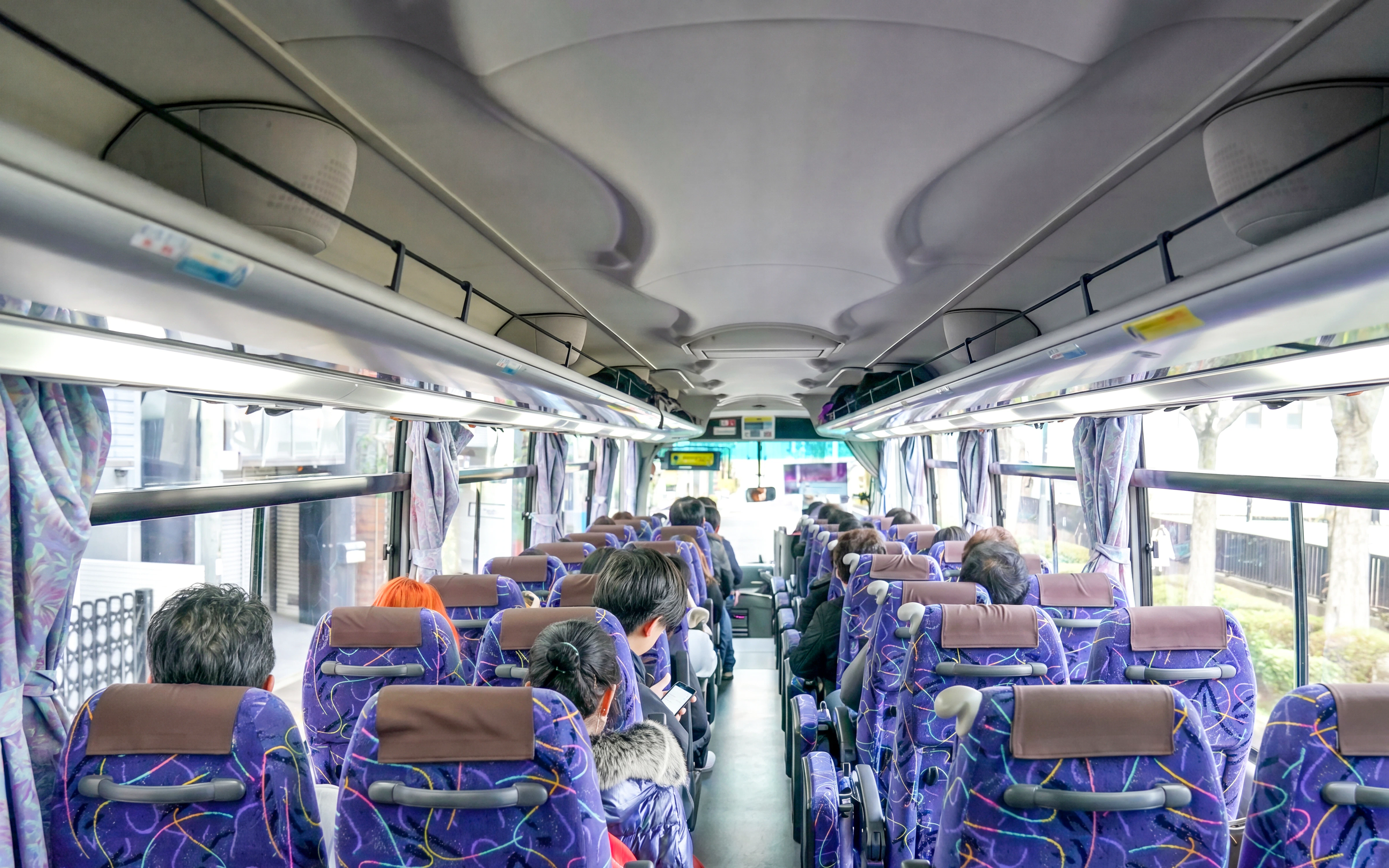 Tourists seated on a bus with a guide during a hotel transfer.