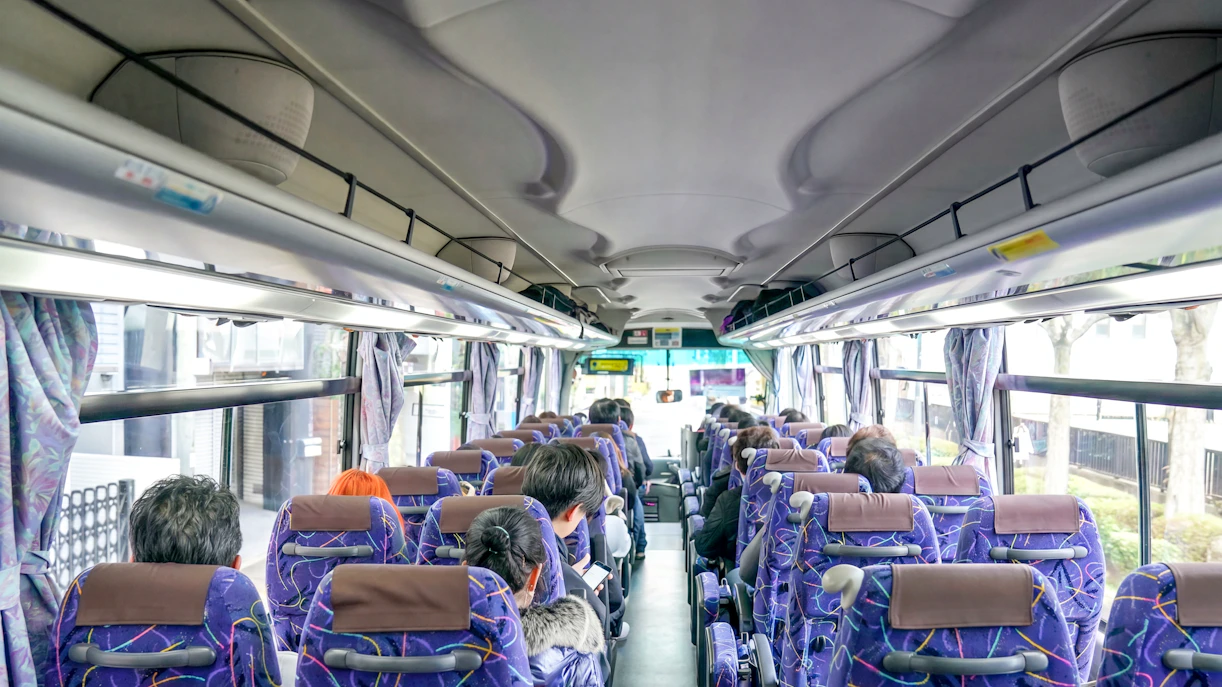 Tourists seated on a bus with a guide during a hotel transfer.