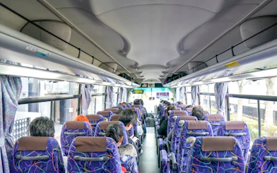 Tourists seated on a bus with a guide during a hotel transfer.