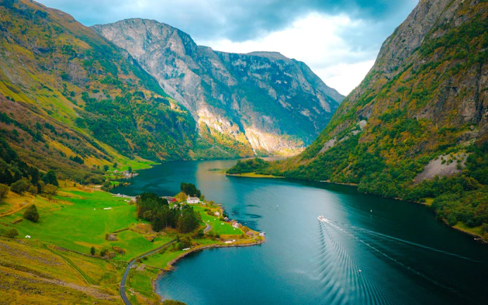 Naeroyfjorden Fjord with boat on water, surrounded by steep mountains and lush greenery.