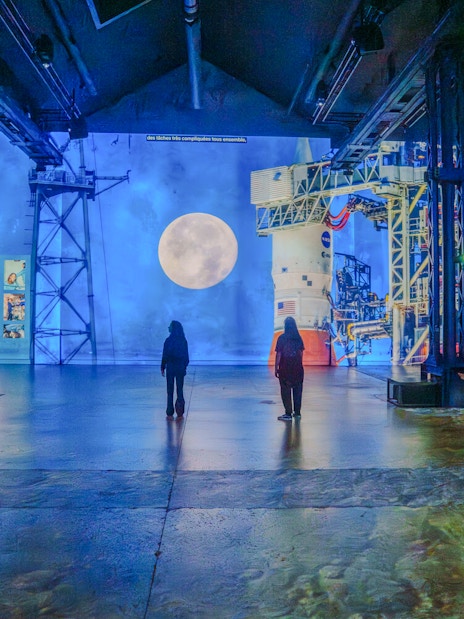 Visitors viewing lunar and space projections at The Moonwalkers Exhibition, Atelier des Lumières.