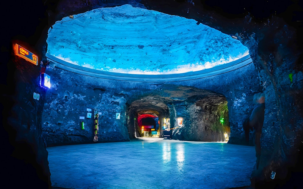 Dome area of Salt Cathedral of Zipaquirá with illuminated blue ceiling.