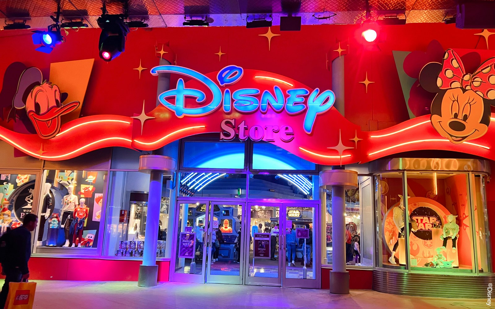 Disneyland Paris shop entrance with colorful lights and character displays.