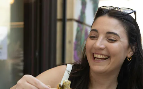 Smiling person enjoying food during Athens evening food tour.