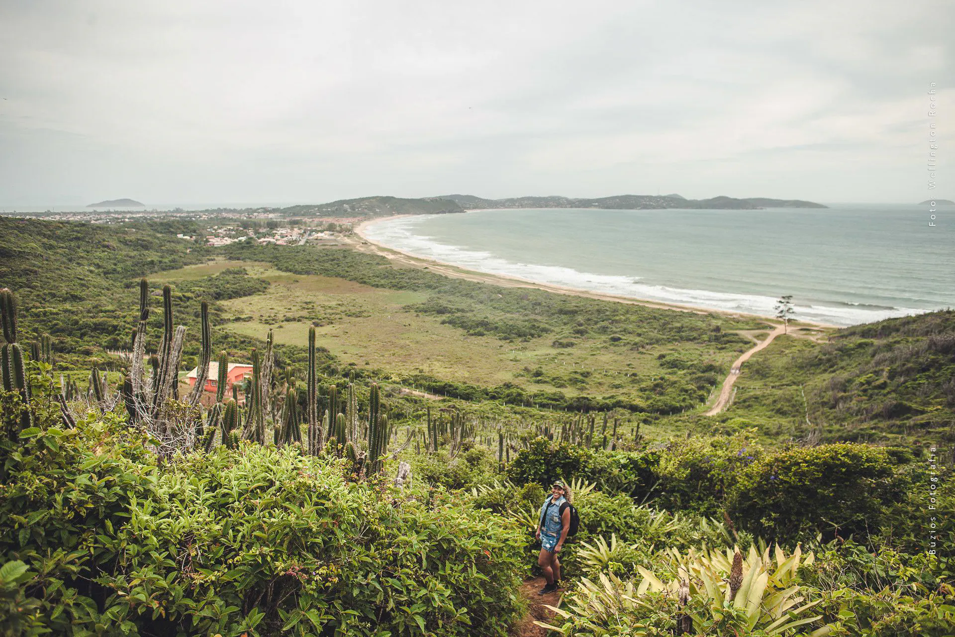 Hiker on a trail overlooking the coastline and greenery in Búzios, Rio de Janeiro.