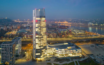 Budapest skyline at night featuring the illuminated MOL HQ skyscraper from a drone view.