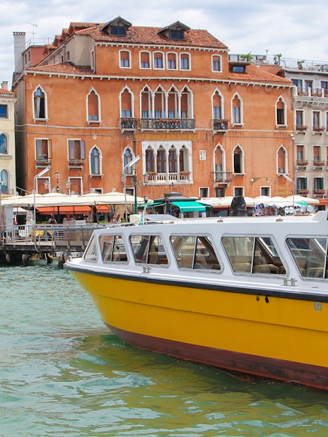 Alilaguna Water Bus docked near colorful Venetian buildings in Venice, Italy.