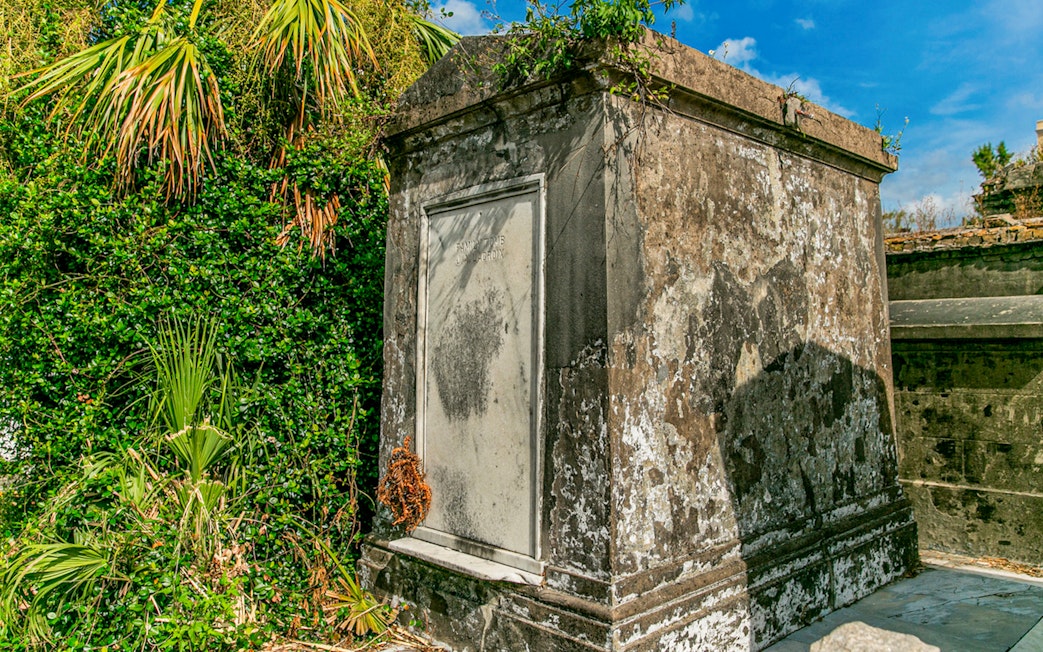 Tomb surrounded by greenery inside St. Louis Cemetery, New Orleans.