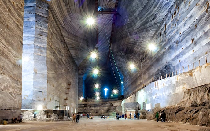 Slanic Salt Mine interior with visitors exploring illuminated cavern, Romania.