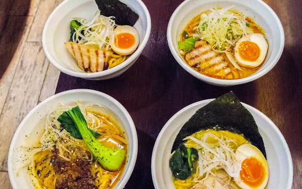 Four bowls of ramen with toppings on a Tokyo Ramen Tasting Tour.