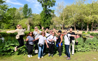 Group enjoying Amsterdam City Highlights Bike Tour in a park with trees and flowers.