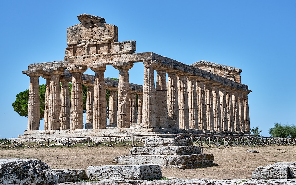 Temple of Athena at Paestum with ancient columns under a clear blue sky.