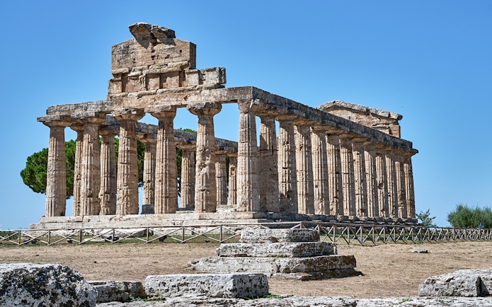 Temple of Athena at Paestum with ancient columns under a clear blue sky.