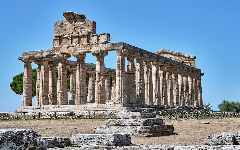 Temple of Athena at Paestum with ancient columns under a clear blue sky.