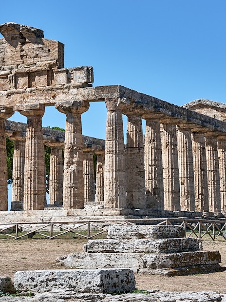 Temple of Athena at Paestum with ancient columns under a clear blue sky.