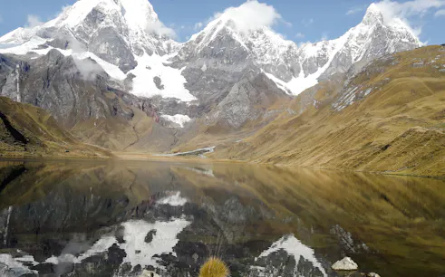 Snow-capped peaks reflected in a lake on the Huayhuash Trek, Peru.
