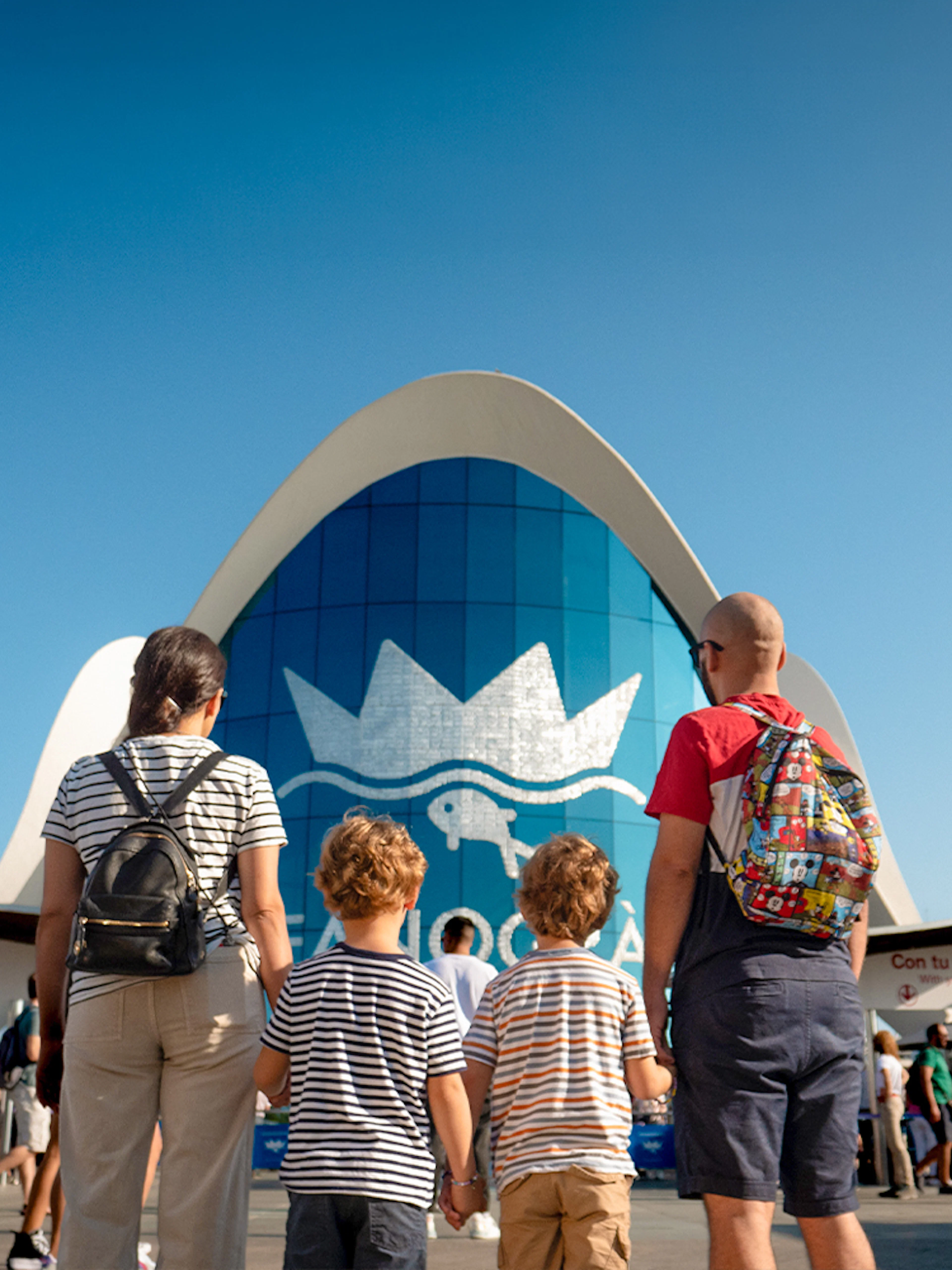 Visitors entering Oceanogràfic Valencia with iconic blue building in background.