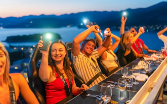 Guests dining at Dinner in the Sky with a view of Dubrovnik at sunset.