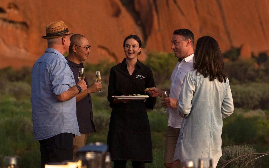 Group enjoying drinks at Uluru with a guide during sunset tour.