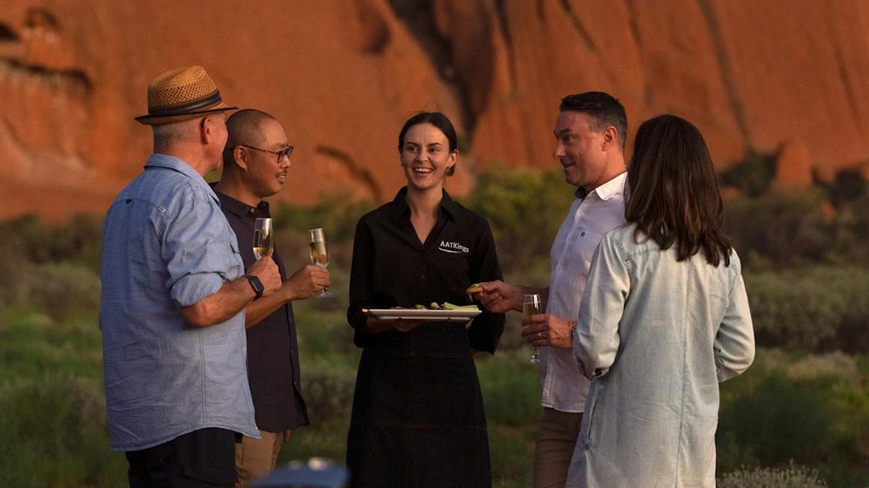 Group enjoying drinks at Uluru with a guide during sunset tour.