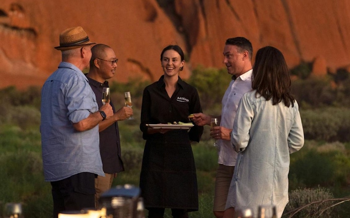 Group enjoying drinks at Uluru with a guide during sunset tour.
