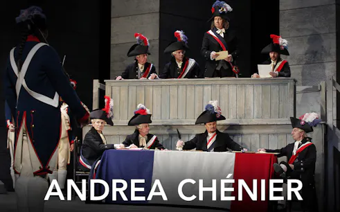 Opera scene from Andrea Chénier with actors in period costumes and tricolor flag.