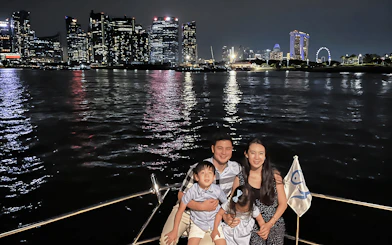 Family enjoying a yacht cruise with Marina Bay Sands and Singapore skyline in the background.