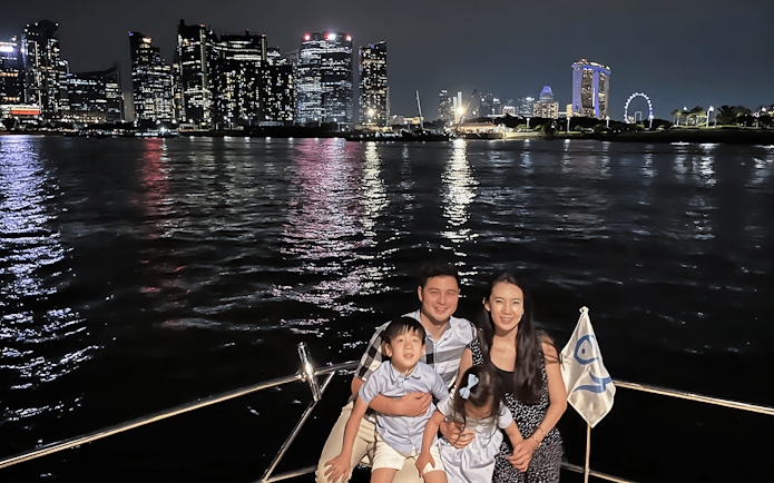 Family enjoying a yacht cruise with Marina Bay Sands and Singapore skyline in the background.