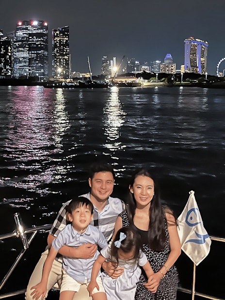Family enjoying a yacht cruise with Marina Bay Sands and Singapore skyline in the background.