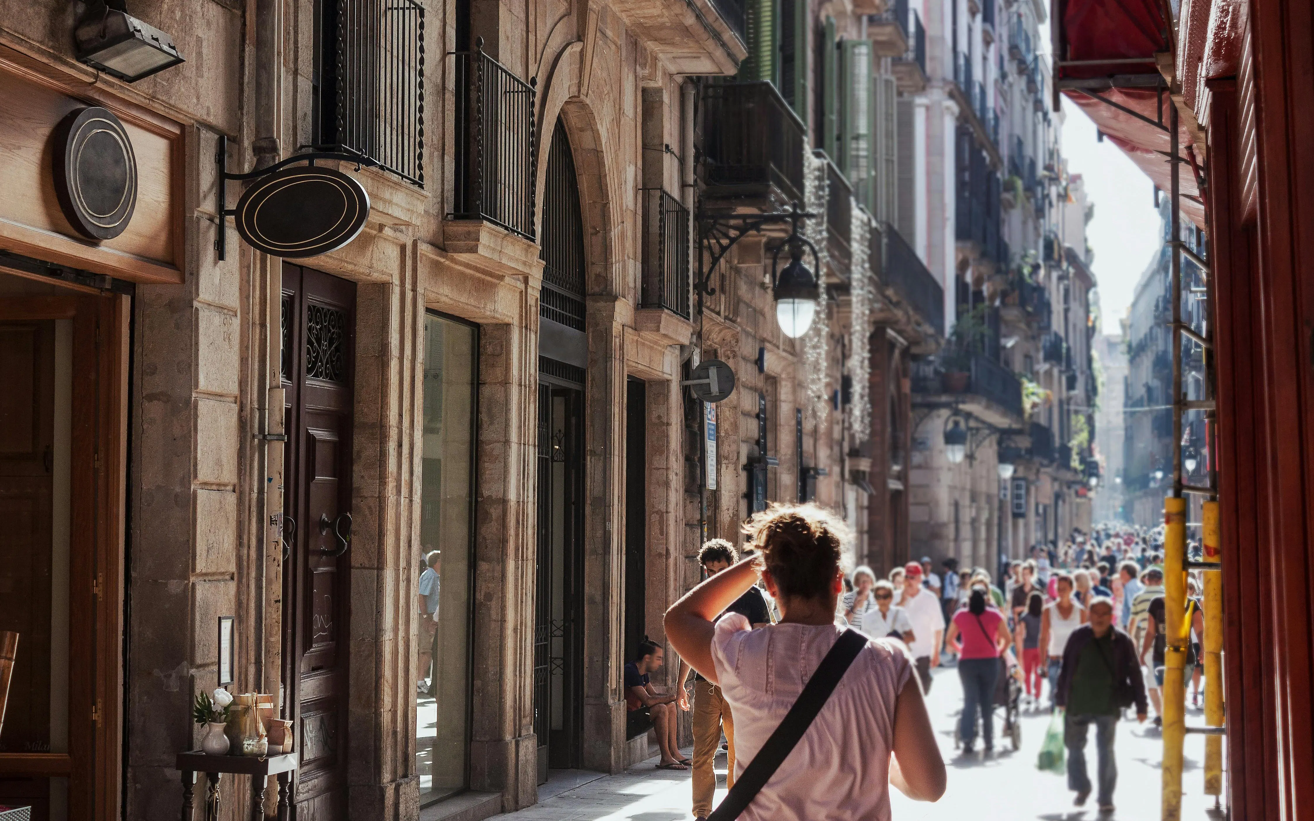 Crowded street in Barcelona's Gothic Quarter shopping area with historic buildings.