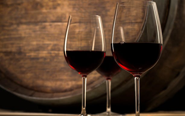 Red wine glasses in front of a wooden barrel at Argiolas Winery, Serdiana.