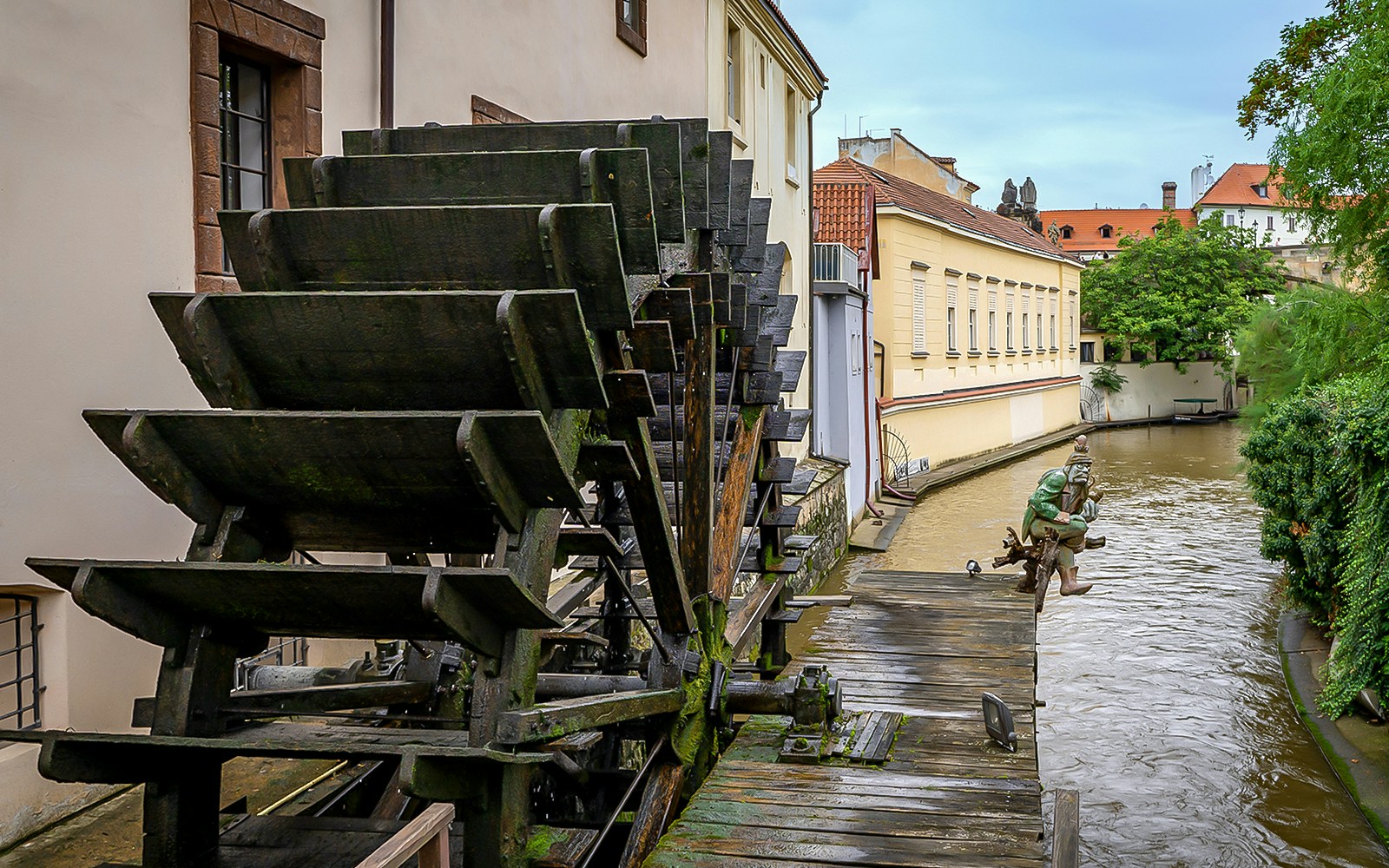 Boat cruising through Devil's Channel in Prague with historic buildings lining the waterway.