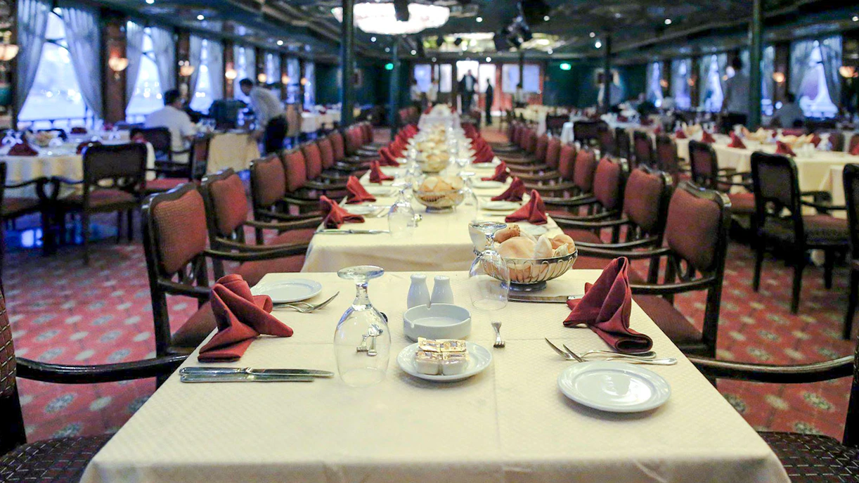 Luxury Nile Dinner Cruise dining area with elegantly set tables and red napkins.