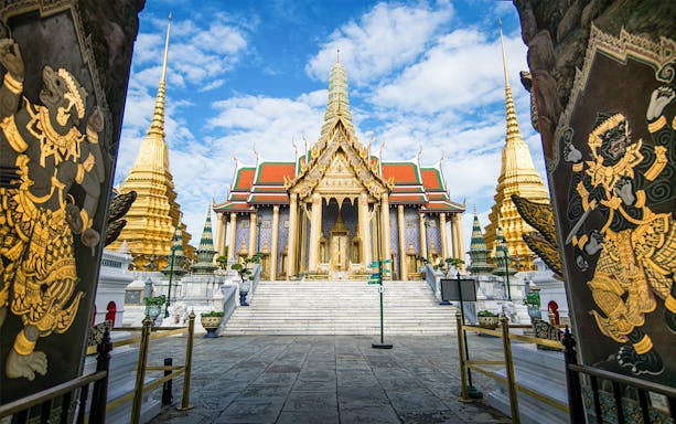 Wat Phra Kaew temple entrance with golden spires in Bangkok, Thailand.