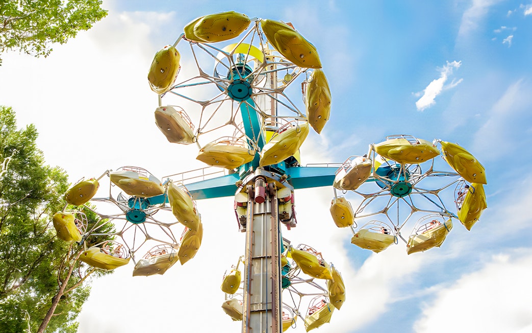 Parque de Atracciones de Madrid Rotor ride with yellow gondolas against blue sky.