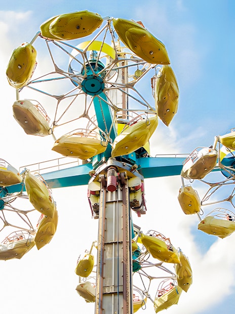 Parque de Atracciones de Madrid Rotor ride with yellow gondolas against blue sky.