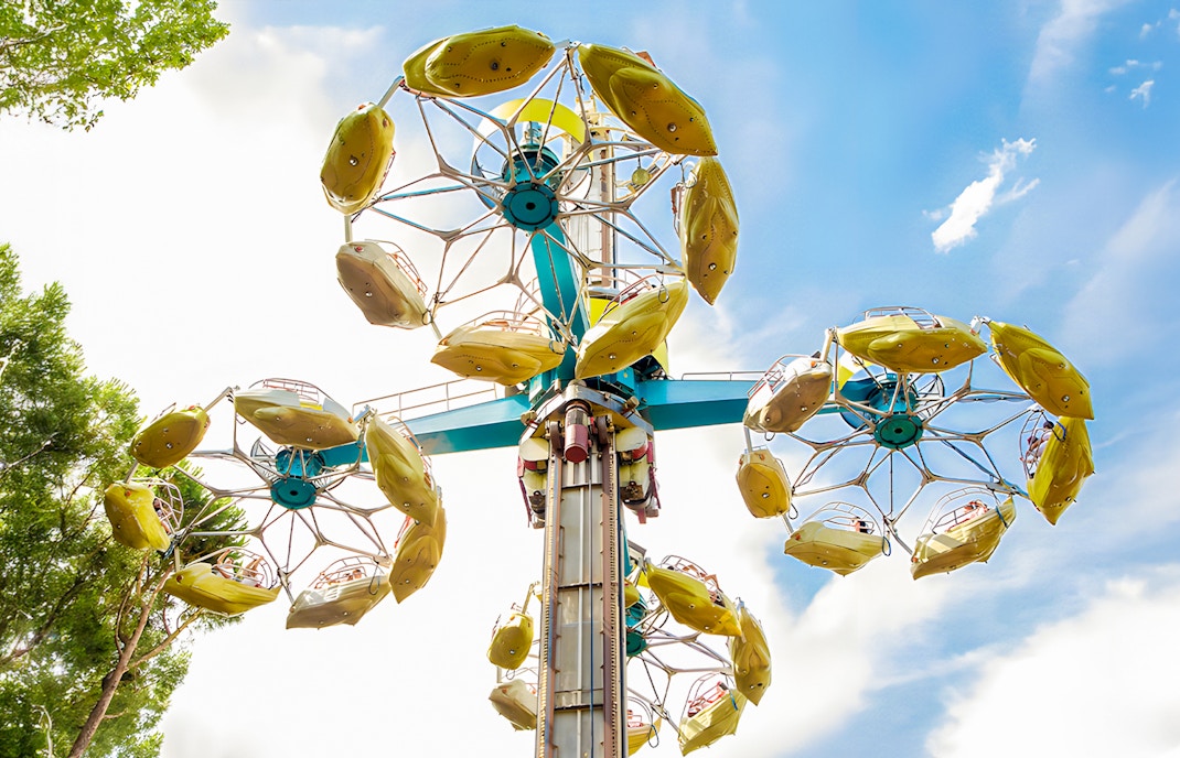 Parque de Atracciones de Madrid Rotor ride with yellow gondolas against blue sky.