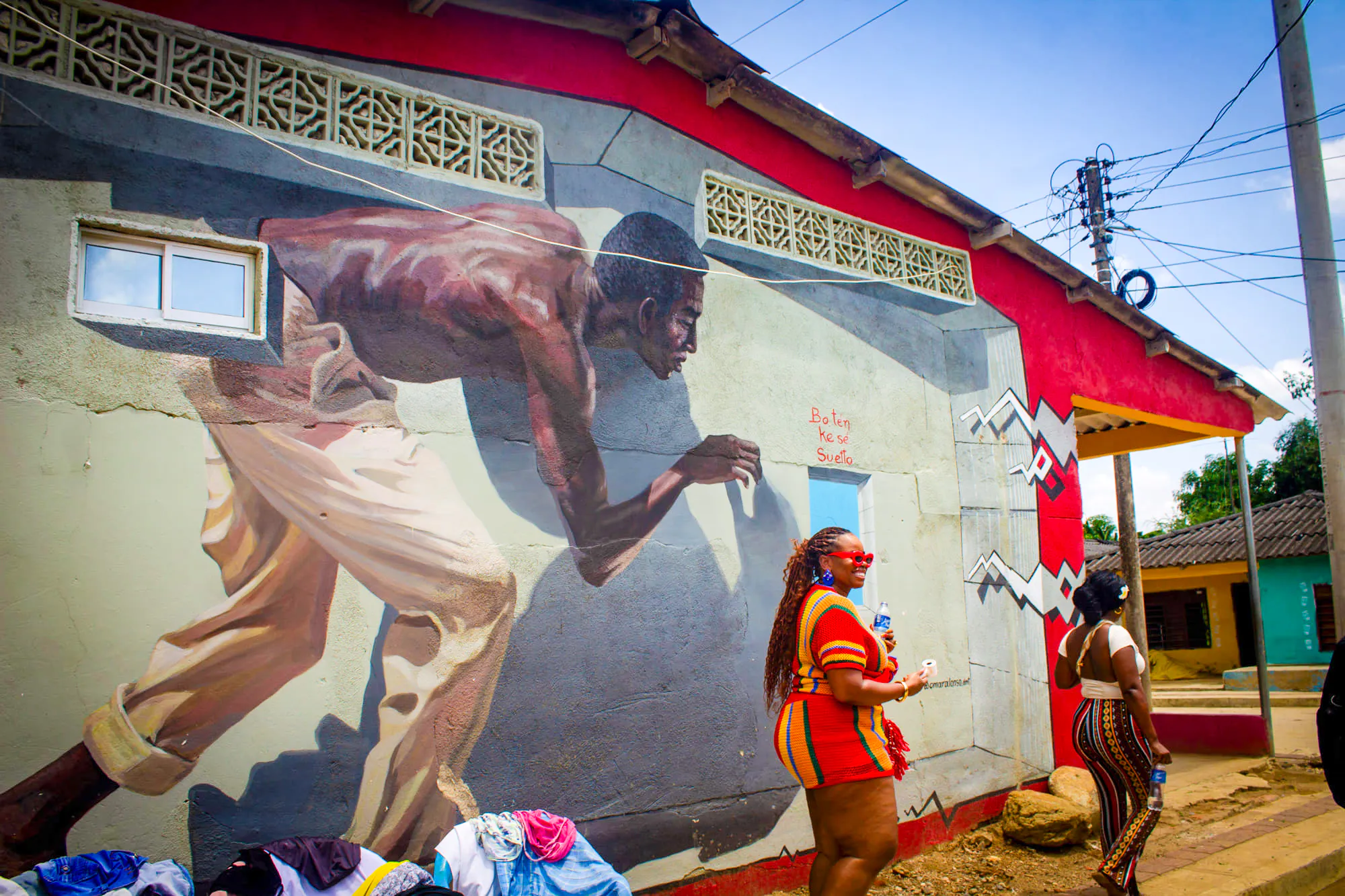 Mural in San Basilio de Palenque depicting a historical figure, with tourists observing.