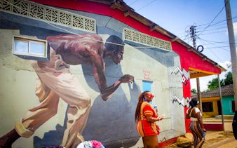 Mural in San Basilio de Palenque depicting a historical figure, with tourists observing.