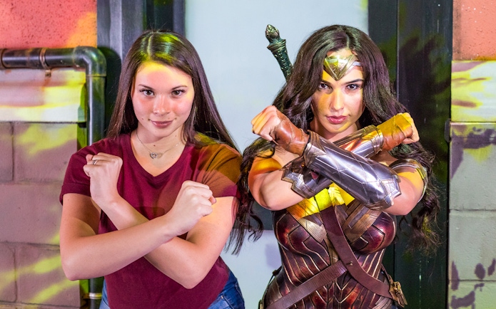 Person posing with a Wonder Woman character at an Orlando attraction.