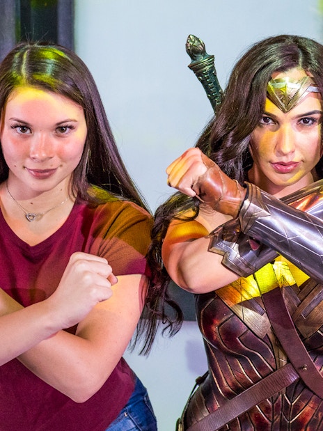 Person posing with a Wonder Woman character at an Orlando attraction.