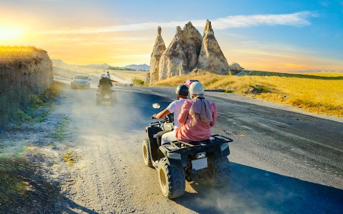 ATV riders exploring Cappadocia's unique rock formations at sunset.